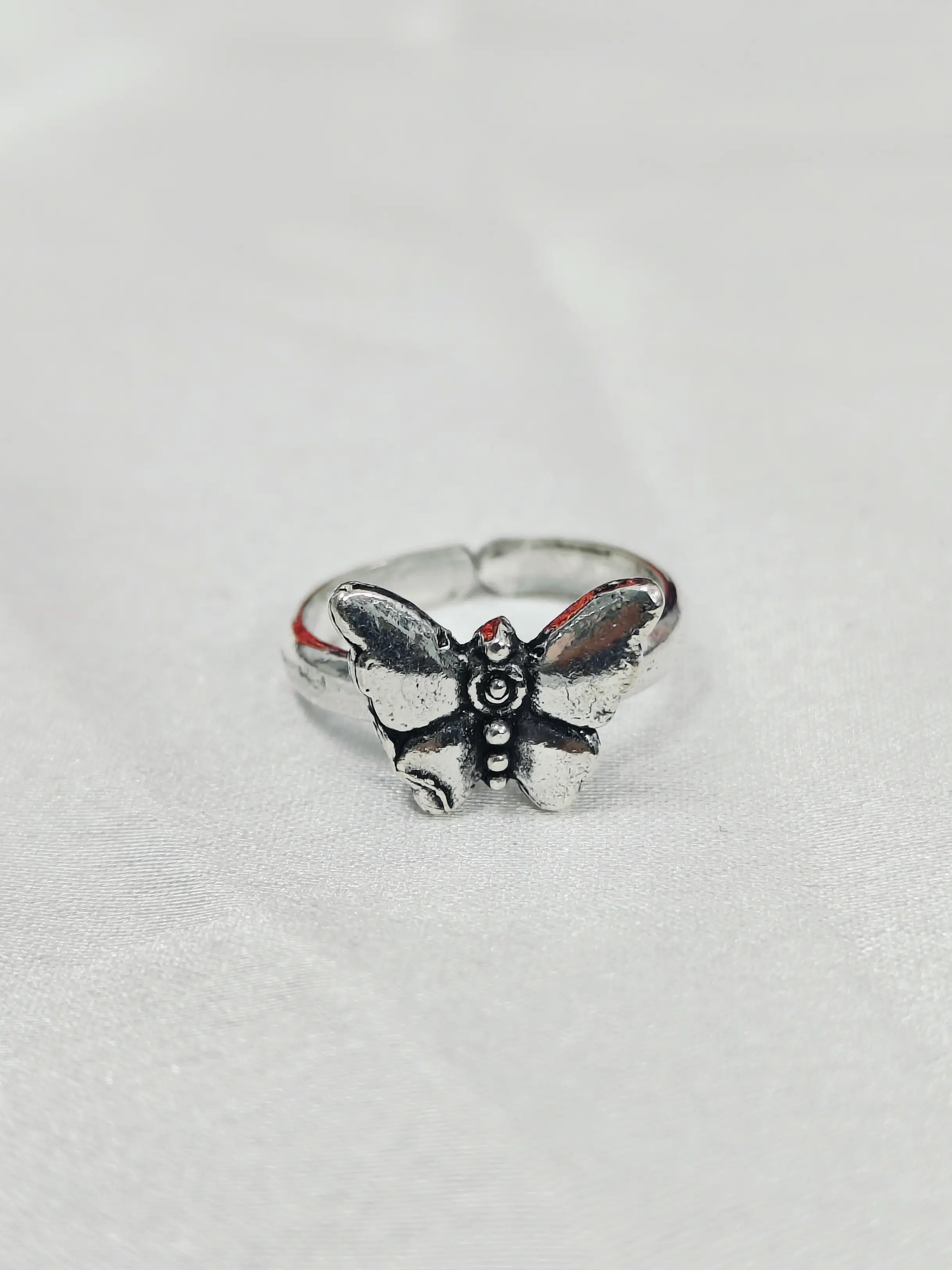 Silver butterfly ring on a light gray background